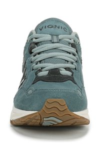 Light teal suede sneaker with grey accents, textured laces, and a rubber sole displaying a wavy tread pattern. Brand name "Vionic" on tongue.