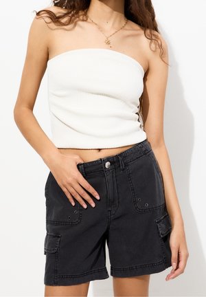 Top blanc à bretelles côtelées sans manches associé à un short cargo noir avec poches avant et fermeture à bouton. Design simple sans motifs.