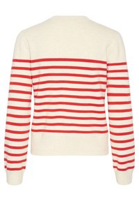 Sweatern har en krämfärgad bakgrund med horisontella röda ränder. Den har en rund hals och långa ärmar, med ribbade muddar och nederkant.