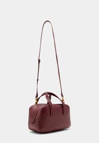 Sac à main en cuir bordeaux de forme rectangulaire, avec deux poignées courtes, une bandoulière réglable et une poche zippée sur le côté.