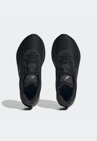 Une paire de chaussures de sport noires avec des dessus en mesh et des lacets, vue de dessus sur un fond gris clair.