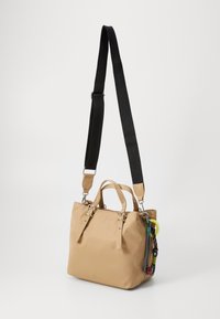 Borsa a tote in nylon beige con tracolla nera regolabile, doppi manici superiori e un portachiavi colorato. Presenta un design minimalista con hardware robusto.