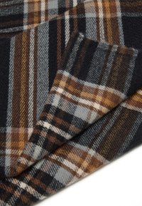 Sciarpa a quadri, caratterizzata da una combinazione di colori blu navy scuro, arancione, grigio e bianco. Texture morbida con motivi a scacchi sovrapposti e bordi sfrangiati.