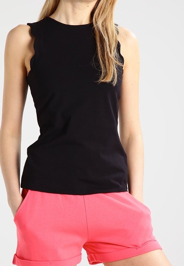 Haut noir sans manches avec un bord en forme d'ondulations aux épaules, associé à un short rose. Le tissu est lisse et le design est décontracté.