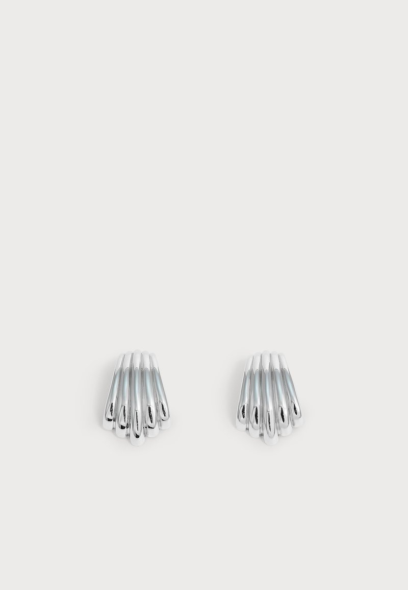 Paire de boucles d'oreilles argentées brillantes avec un design à barrettes courbées superposées, affichées sur un fond clair uni.