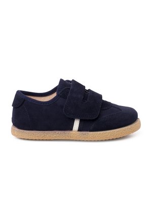 Marineblauwe suède kinderschoen met een brede klittenbandsluiting, beige rubberen zool en een gestructureerd oppervlak. Casual ontwerp, lage snit.