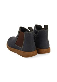 Botas de ante azul marino hasta el tobillo con paneles elásticos laterales, acentos marrones y suela de goma, con costuras blancas y una cinta para tirar.