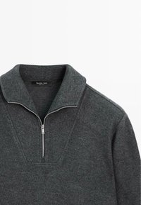 Tmavě šedý fleecový pulovr s půlzipem u výstřihu, s texturovaným povrchem a strukturovaným designem límce. Uvnitř viditelná štítek.