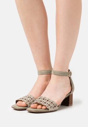 Sandales à talons en daim gris, avec bout ouvert, dessus géométrique découpé, bride à la cheville avec boucle, et talon bloc en bois.