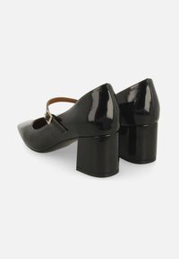 Scarpe in vernice nera con tacco a blocco, punta affusolata, cinturino alla caviglia e dettaglio con fibbia, con una finitura liscia e lucida.