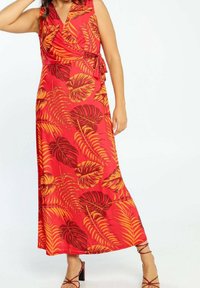 Robe maxi rouge à design portefeuille, arborant de grands motifs de feuilles orange et rouge foncé. Se noue à la taille, tissu lisse, style sans manches.