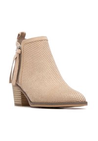 Botín beige perforado con punta fina, cremallera lateral y tacón apilado de madera. Material de ante suave con textura lisa.