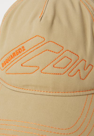 Beež müts, mis on valmistatud tekstureeritud kangast, featuring julge oranž õmblus ja brodeeritud logo. Kõver serv ja reguleeritav tagaosa.