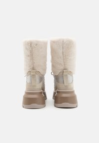 Chunky beige støvler med pelsoverdel, mesh-detaljer og teksturerede såler. Udstyret med en polstret skaft og kontrastmateriale-detaljer.