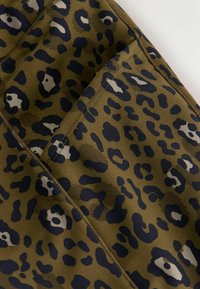 Õliv roheline kangas musta leopardi trükikujundusega. Omab siledat tekstuuri ja nähtavat õmblust servade ääres.