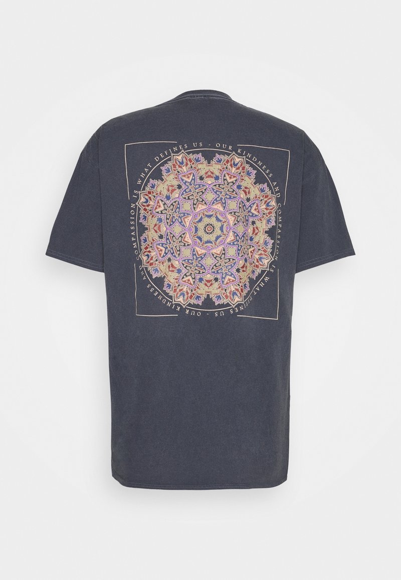 Camiseta de algodón azul marino con un gran estampado gráfico circular multicolor en la parte posterior, que presenta patrones ornamentales y texto. Manga corta, cuello redondo.