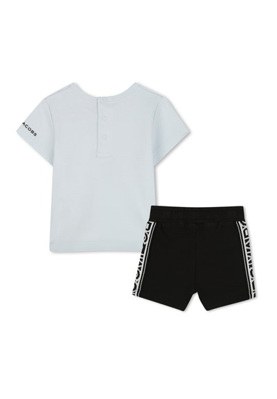 T-shirt azzurro chiaro a maniche corte con tre bottoni sul collo, abbinato a pantaloni corti neri con strisce bianche laterali e cintura elastica.