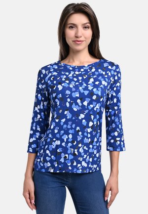 Blau gemusterte Bluse mit Dreiviertelärmeln, die abstrakte Formen in Blau-, Weiß- und Schwarztönen zeigt. Weicher Stoff, lockere Passform.