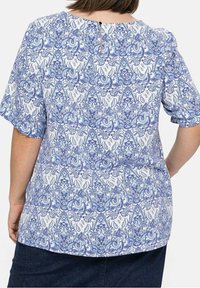 Blaue und weiße Bluse mit Muster, kurzen Ärmeln, lockerer Passform, einem Rückenschlitz und dekorativen Kurven und Formen im Design.