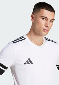 White athletic t-shirt made of smooth fabric, featuring black three-stripe accents on the shoulders and a black logo on the chest.