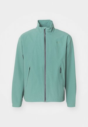 Light green softshell jacket with a high collar, front zipper, and two side pockets. Minimalist design with a textured finish.