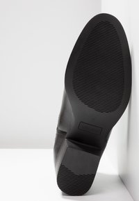 Suola di scarpa in pelle nera con grip testurizzato, tacco a blocco, taglia 37, e il marchio "Anna Field" visibile sul fondo.