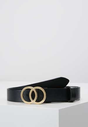 Zwarte leren riem met een gouden dubbele ringgesp, plat gelegd op een witte ondergrond tegen een effen achtergrond.