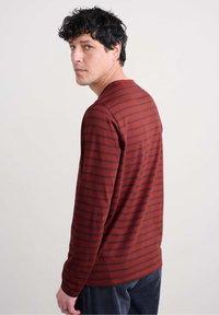 Pitkähihaisessa tummanpunaisessa paidassa on mustia raitoja. Pehmeä kangas, rento malli, pyöreä pääntie, näkyvät ompelutiedot. Paita on päällä henkilöltä näkyy takaa.