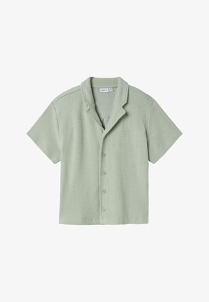 Lühikese varrukaga nööbid-up särk helesinisest tekstuuriga kangast, millel on sälguga krae ja viis esimist nööpi, omades mugavat lõiget.