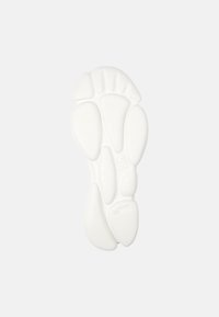 Podeszwa trampka, biała, teksturowana guma z różnymi wypukłościami i rowkami, zaprojektowana dla przyczepności i komfortu. Numer '36' wytłoczony na pięcie.