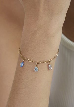 Goldkettchen-Armband mit drei Anhängern: ein blauer Tropfen, eine hellblaue Birne und ein klarer rechteckiger Stein.