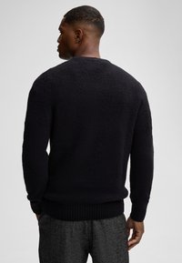 Dunkelgrauer Strickpullover mit einer strukturierten, flauschigen Oberfläche. Verfügt über lange Ärmel, einen runden Ausschnitt und gerippte Bündchen sowie Saum.