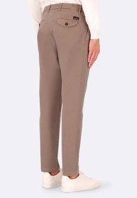 Pantaloni beige a gamba dritta in cotone con tasca posteriore dotata di bottone, abbinati a sneaker bianche. Design pulito e sartoriale.
