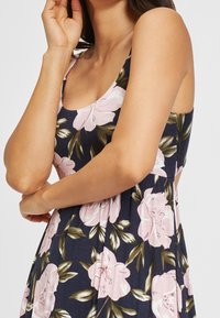 Sukienka w kwiaty z ciemnogranatowym tłem, z dużymi różowymi kwiatami i zielonymi liśćmi, wykonana z miękkiego, lekkiego materiału.