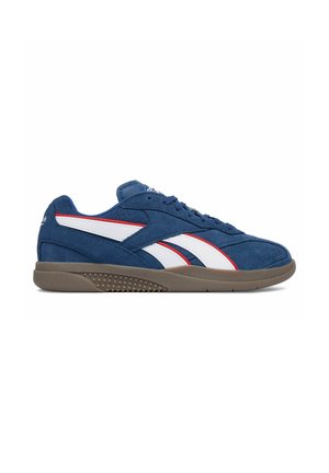 Niebieski zamszowy sneaker z białymi i czerwonymi paskami oraz brązową, fakturowaną podeszwą, pokazany z zewnętrznej strony na białym tle.