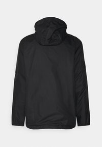 Svart huva jacka med långa ärmar och elastiska manschetter, visad bakifrån på en enfärgad ljus bakgrund.