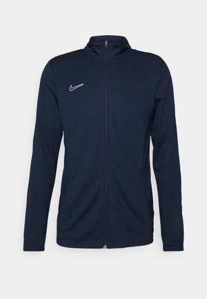 Navy blue athletic jacket with a stand-up collar, full front zipper, side pockets, and white Nike logo on the upper left side.