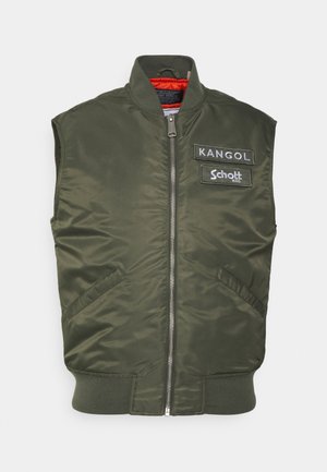 Jaqueta bomber sem mangas em verde-oliva com fecho frontal, bolsos laterais e patches bordados da Kangol e Schott. O interior é de um laranja vibrante.
