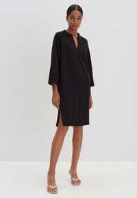 Black dress with a V-neck, three-quarter sleeves, side slits, and a loose fit. Smooth texture with a minimalistic design.