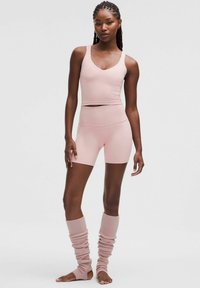 Lyserød atletisk sæt bestående af en cropped tanktop og højtaljede shorts. Ribbede benvarmere i matchende farve fuldender outfittet.