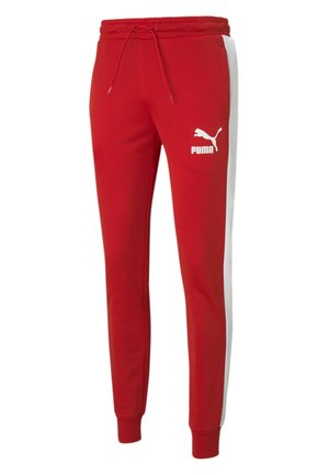 Red sweatpants made of fabric with a smooth texture. Features white side stripes and a small white Puma logo on the left thigh.