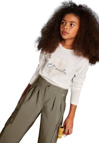 Camicia bianca a maniche lunghe con testo blu "Et voilà" abbinata a pantaloni cargo verdi oliva plissettati con tasche laterali e bottone.