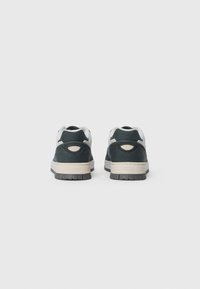 Dunkelgrüne Sneaker mit einer strukturierten Oberseite, weißen Akzenten und einer beigen Zwischensohle. Die Gummisohle zeigt ein gemustertes Profil für besseren Halt.
