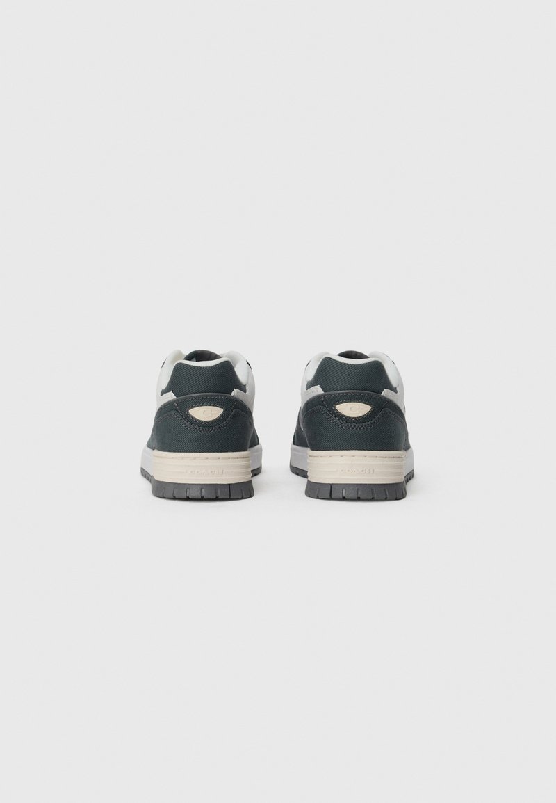Dark green sneakers with a textured upper, white accents, and a beige midsole. The rubber outsole shows a patterned tread for grip.