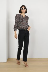 Long-sleeve, button-up shirt with a multicolored abstract pattern, paired with black straight-leg pants and brown heeled sandals. White cat-eye sunglasses.