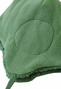 Green fleece hat with circular patch detail, soft texture, and knit trim. Features a drawstring for adjustment.