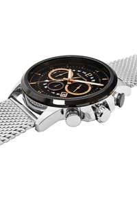Kronografklocka med svart urtavla, silverfärgad nätarmband, guldackenter och tre subdials. Har ett hus i rostfritt stål och texturerad krona.