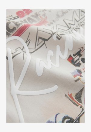 Tissu en coton avec une surface texturée présentant un "R" cursif blanc et des motifs graphiques colorés dans différentes teintes sur un fond clair.