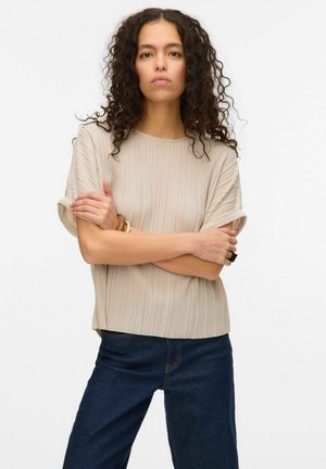 Beige plissé blouse met een ronde hals en korte mouwen, gecombineerd met donkerblauwe denim jeans. Glad textuur van de stof; eenvoudig ontwerp.