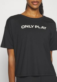 Camiseta negra de manga corta con cuello redondo que presenta el texto "ONLY PLAY" en letras blancas de contraste en el pecho.